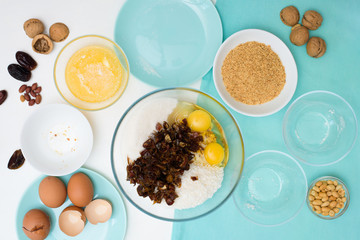 ingredients for the recipe homemade oatmeal cookies with dates, peanuts , coconut shavings, eggs, flour, salt in glazed plates on a light background. the view from the top