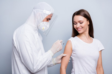 Photo of cheerful patient lady guy expert virology inject shoulder covid antidote experimental vaccine wear mask hood uniform plastic facial protection isolated grey color background