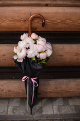 
Delicate flowers of pink and white peonies in a vase from an umbrella from the rain with a pink ribbon. A bouquet of flowers to decorate the interior. Floristry