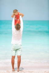 Little girl and happy dad having fun during beach vacation