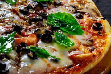 Italian fresh delicious pizza with black olives basil leaves boiled corn cheese