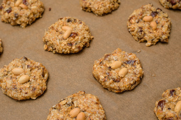 homemade oatmeal cookies with dates, peanuts , coconut shavings on a baking tray, close-up. the view from the top