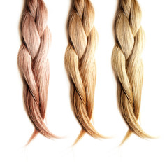 Healthy, shiny hair is braided on a white background. Hair samples of different shades.