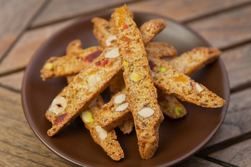 homemade Biscotti with nuts and candied fruits on a brown plate on a wooden table