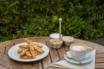 a plate of homemade biscotti cookies and a Cup of coffee with cream and sugar on the wooden table. Blurred background