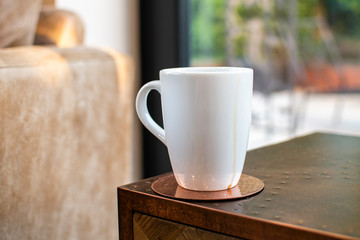 Coffee or tea cup with a spill down the side on a copper coaster in a modern kitchen