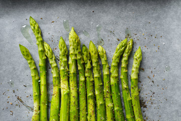 Green asparagus on the oven baking tray. Bundle of ripe fresh asparagus. Healthy organic food. Cooking in home. Natural vitamins, raw ingredient for eating. Handpicked bio asparagus