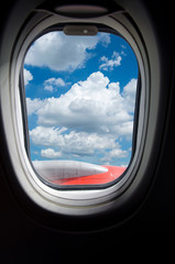 Airplane window with blue sky and cloud view