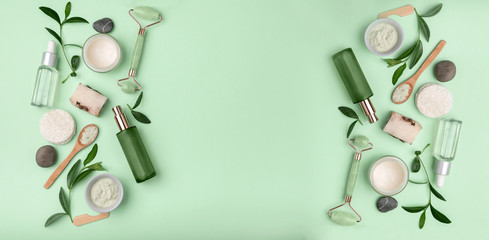 Green spa or wellness layout frame. leaves and body and face care tools and accessories on Green background, top view. Beauty background with various eco friendly cosmetic and skin care products