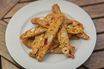 homemade Biscotti with nuts and candied fruits on a white plate on a wooden table