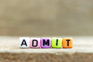 Colorful bead with black letter in word admit on wood background