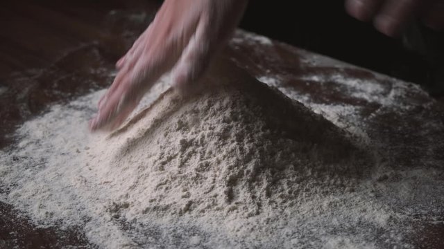 Flour is falling on the black table in slow motion. Someone throwing flour on a dark background. Slow motion of falling white flour on the black background.