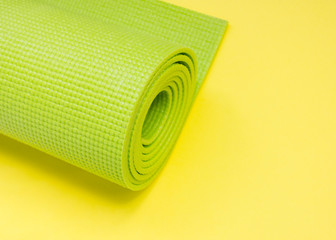 A green yoga pilates exercise mat rolled up. International Yoga Day June 21st. love yoga.Sport indoors