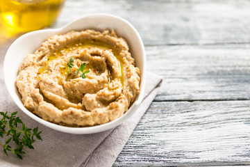 hummus sauce in a bowl, sesame seeds, olive oil, cucumber and carrots on a light background