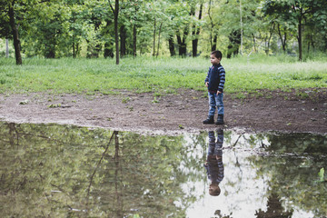 Little boy standing in the park near lake