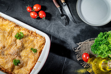 Traditional italian lasagna with vegetables, minced meat and cheese On a dark background. Homemade meat lasagna