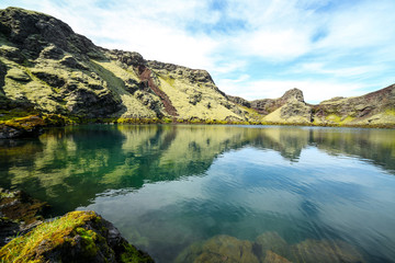 Volcanic lake inside of a crater in Iceland. Volcanic crater lake in southern Iceland. Highland of Iceland. Beautiful crater lake with a turquoise water color covered with green moss