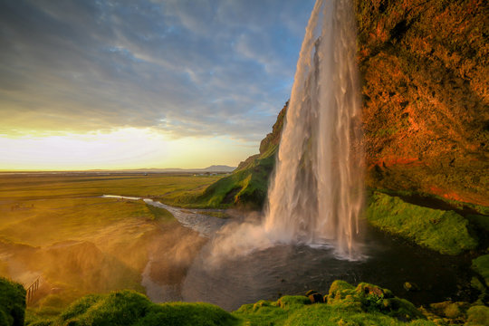 Waterfall Selandjafoss Iceland at sunset or sunrise. Beautiful waterfall in Iceland. Golden hour. Cave and waterfall. Travel in Iceland. Beautiful sky against the big waterfall. inside the water. © Epic Vision