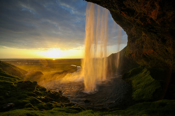 Waterfall Selandjafoss Iceland at sunset or sunrise. Beautiful waterfall in Iceland. Golden hour. Cave and waterfall. Travel in Iceland. Beautiful sky against the big waterfall. inside the water. 