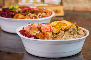 Deliver food, marmita ou marmitex with rice, beans, beets, broccoli, mayonnaise with vegetables, fried chicken, beef stroganoff, pasta and bacon on a dark marble table.