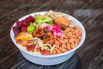 Deliver food, marmita ou marmitex with rice, beans, beets, broccoli, mayonnaise with vegetables, fried chicken, beef stroganoff, pasta and bacon on a dark marble table.