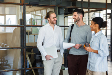 Photo of multinational pleased colleagues talking and smiling