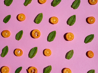 A lovely  collage of sliced Chinese mandarins and mint leaves on a light pink background in a concept of freshness, healthy lifestyle and detox diet in spring and summer.