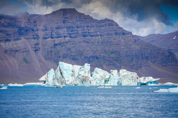 Icebergs floating. Ices and volcanic ash. Glacier lagoon. Melting ice. South coast Iceland.Volcanic ash on the arctic ice. Ice age glacier crevasse melting fast. Global warming. The edge of a glacier