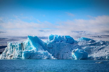 Fototapeta na wymiar Icebergs floating. Ices and volcanic ash. Glacier lagoon. Melting ice. South coast Iceland.Volcanic ash on the arctic ice. Ice age glacier crevasse melting fast. Global warming. The edge of a glacier
