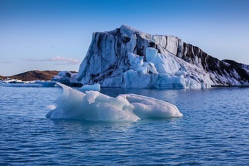 Fototapeta na wymiar Icebergs floating. Ices and volcanic ash. Glacier lagoon. Melting ice. South coast Iceland.Volcanic ash on the arctic ice. Ice age glacier crevasse melting fast. Global warming. The edge of a glacier