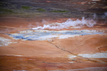 Geothermal region of Hverir in Iceland near Myvatn Lake, Iceland. Sulfur colored land and red roicks creek with steam. Volcanic rocks. Lava field. Icelandic volcanic mountain expanse of hot springs