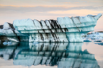 Icebergs in the ocean. Golden hour ligt over the Vatnajokull glacier. Amazing landscapes and huge icebergs. Icebergs with lava layers floating. Melting Ice. Global warming concept Iceland