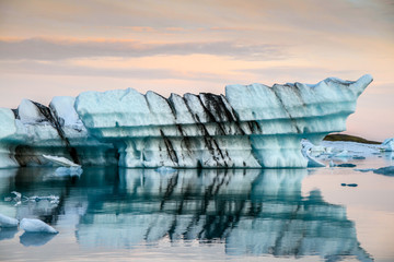 Icebergs in the ocean. Golden hour ligt over the Vatnajokull glacier. Amazing landscapes and huge icebergs. Icebergs with lava layers floating. Melting Ice. Global warming concept Iceland