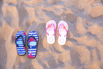 a pair of male and female flip flops in the sand on the beach