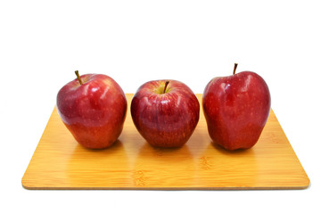 three apples isolated place on woodden cutting board.
