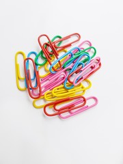 Multicolored metal paper clips on a white background.