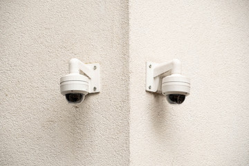 Two security cameras on a white wall