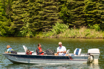Grandpa fishing with his grandchildren on a boat in summer