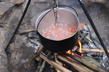 Mulled wine cooked on fire outdoors. Picnic. Romantic getaway near the fire.