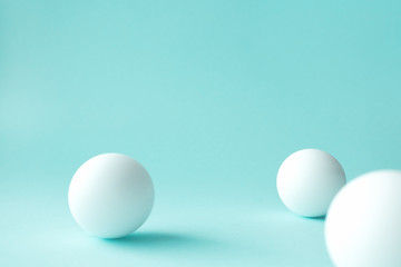 White ping pong balls on mint green background with selective focus, some defocused. Abstract backgrounds with geometric sphere shapes and copy space for text on top