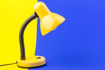 Yellow desk lamp isolated on blue and yellow background