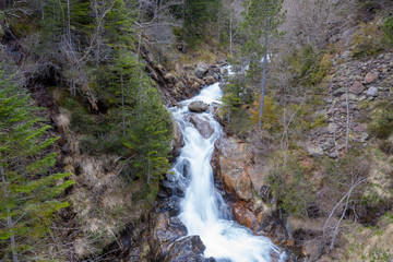 Alpine waterfall in Andorra streaming down a mountain surrounded by beautiful nature and trees