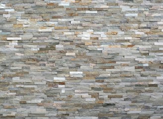 Stone wall cladding made of stacked stripes rocks. The colors are from white to gray and brown. Background, close up.