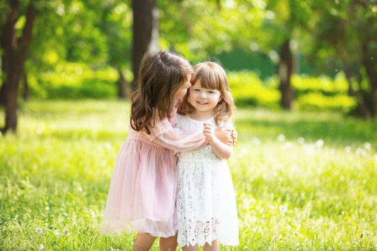 Two small beautiful girls children together happy play and laugh in nature