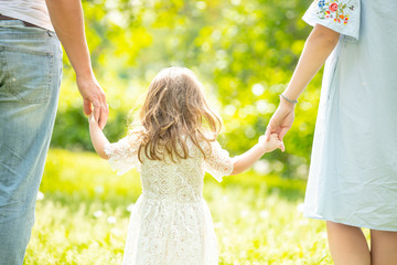 Little girl a child on a walk with her parents holding their hands behind their back