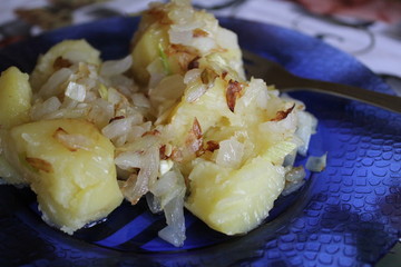 boiled potatoes with fried onions on a blue plate, home-made food