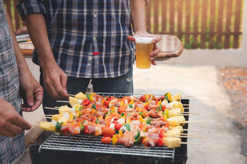 A man grilling pork and barbecue in dinner party. Food, people and family time concept.