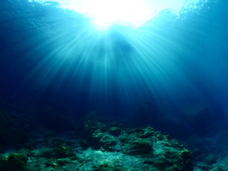 Fototapeta na wymiar sun beams sun rays and sun shine on rocks underwater