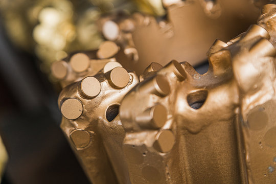 Macro shot of drill bits on shelving in stock. Oil drilling equipment for drilling rig operation on oil platform in oil and gas industry. Brand new PDC Polycrystalline Diamond Compact drilling bit