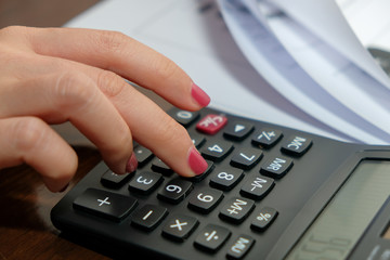 Financial data analyzing hand writing and counting on calculator at home on wooden desk,Business and finance concept..